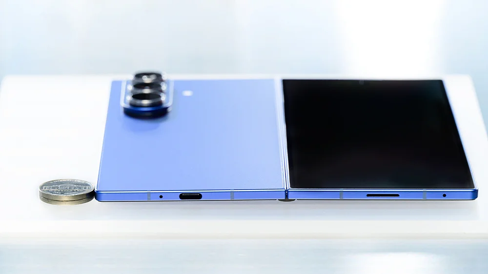 Galaxy Z Fold da Samsung totalmente aberto ao lado de uma moeda, mostrando como um dobrável fica fino quando desdobrado
