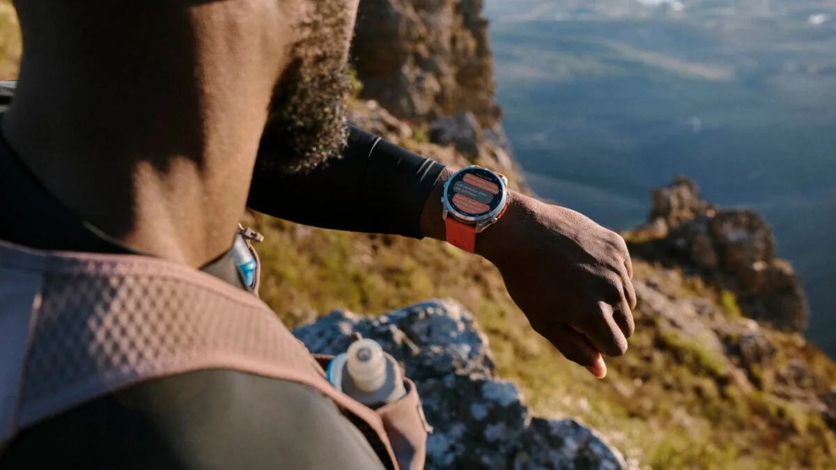Pessoa correndo em trilha de montanha, conferindo dados no Garmin fenix 9 no pulso