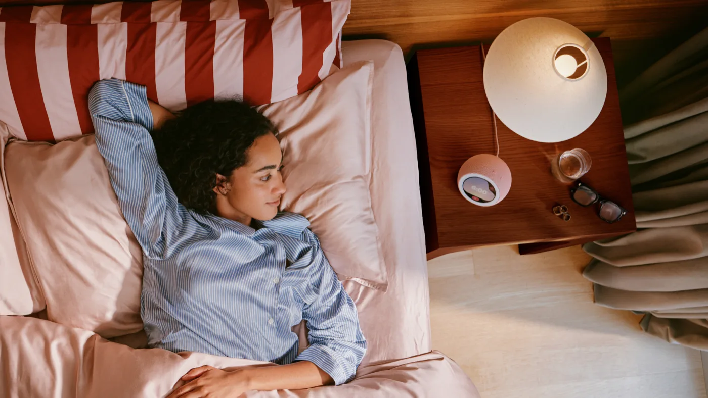 Mulher dormindo em uma cama, com o Echo Time na mesa de cabeceira