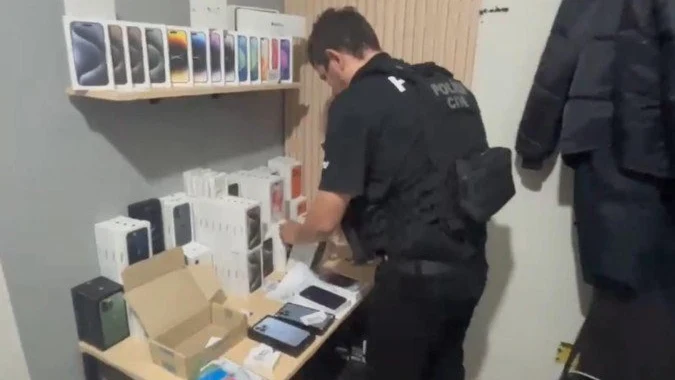 Policial da PCDF examina caixas de iPhone apreendidas na operação contra a loja falsa de celulares