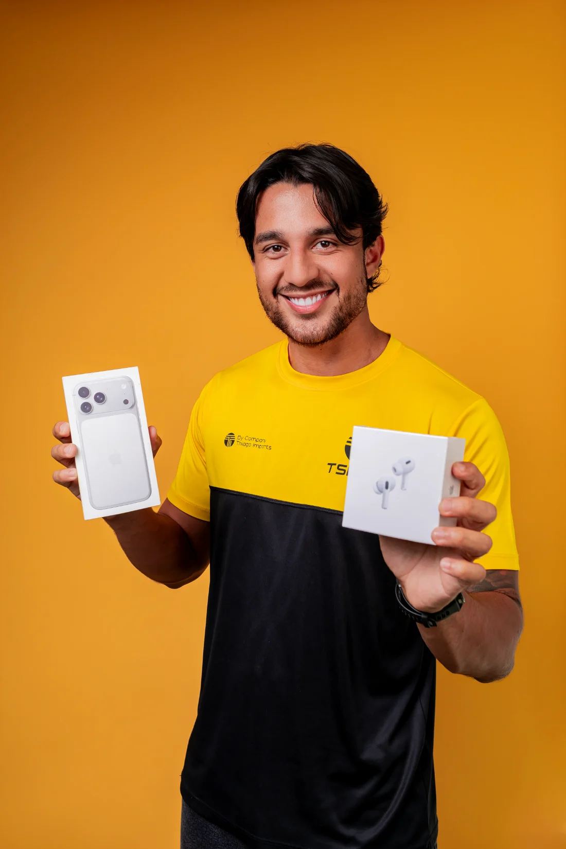 Thiago segurando um iPhone e um AirPods ainda lacrados na caixa